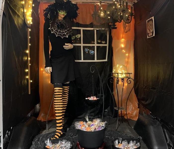Back of a truck. With lights strung, a mannequin dressed up as a witch and candy in plastic cauldron 